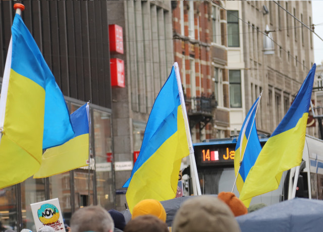 Oekraïense vlaggen worden om hoog gehouden tijdens een mars in Amsterdam