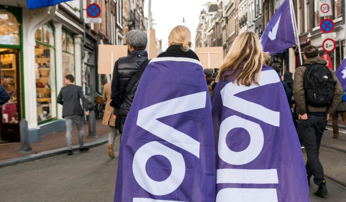 2 mensen lopen met een volt vlag op hun rug