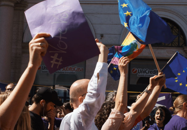 Mensen houden Europese en pride vlaggen omhoog. Ook een papiertje met #Vote Volt